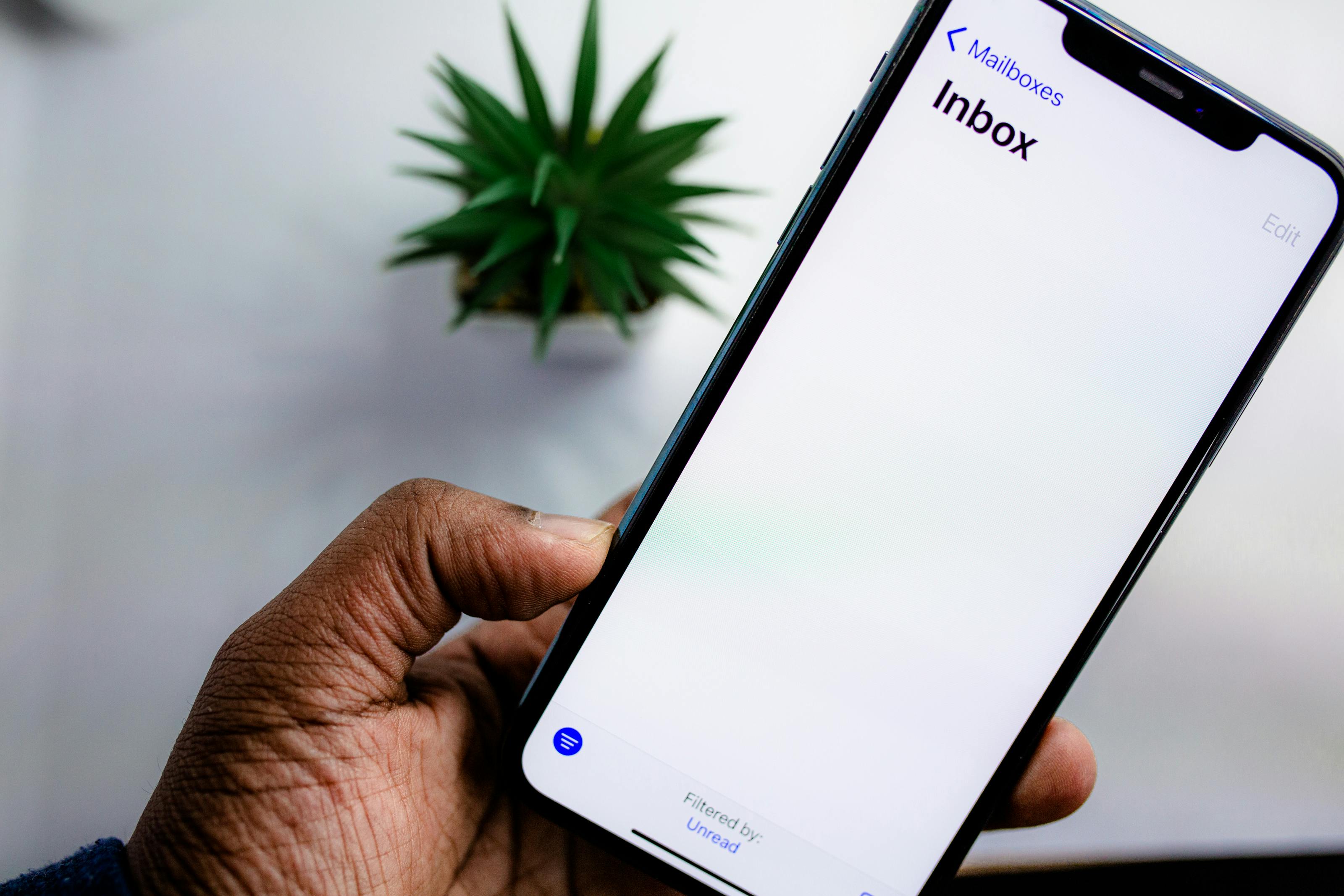 Hand houdt smartphone vast met geopende e-mail-inbox waarin merklogo's naast berichten zichtbaar zijn dankzij BIMI